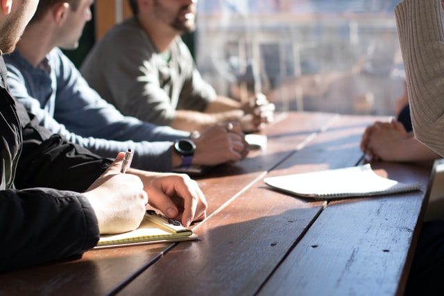 Close up of small group of cybersecurity professionals taking notes around a table