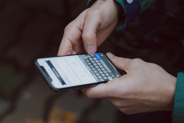 Hands typing onto a cellphone keyboard