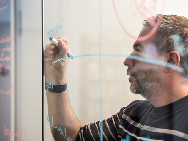 Cybersecurity professional writing with marker on clear whiteboard